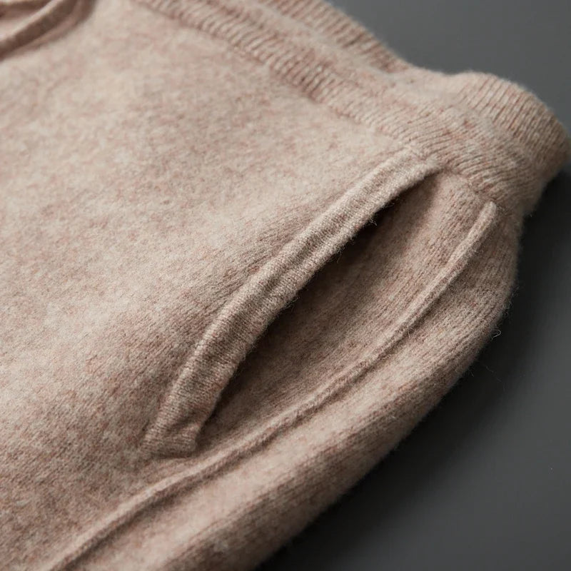 Close-up view of the side seam welt pocket structure on soft beige wool knit sweatpants.