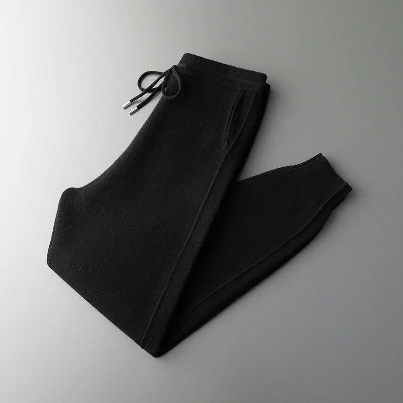 Neatly folded black wool knit sweatpants displayed against a grey background.