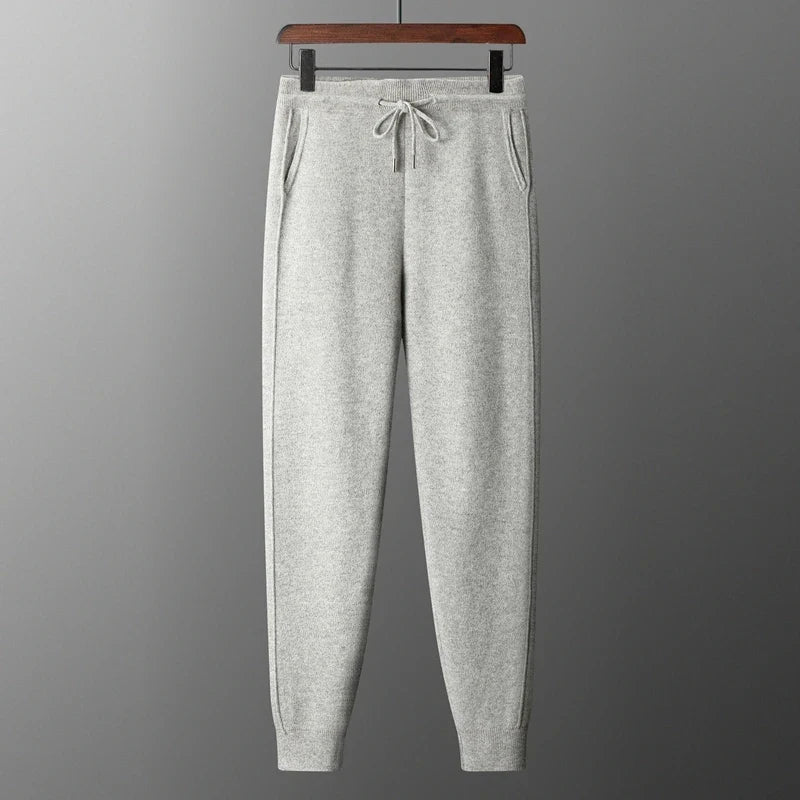 Front view of light gray heathered wool knit sweatpants hanging on a hanger, featuring a drawstring waist and tapered leg cuffs.