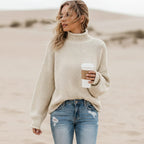 Cream chunky knit turtleneck sweater with balloon sleeves and an oversized fit, worn with distressed denim.
