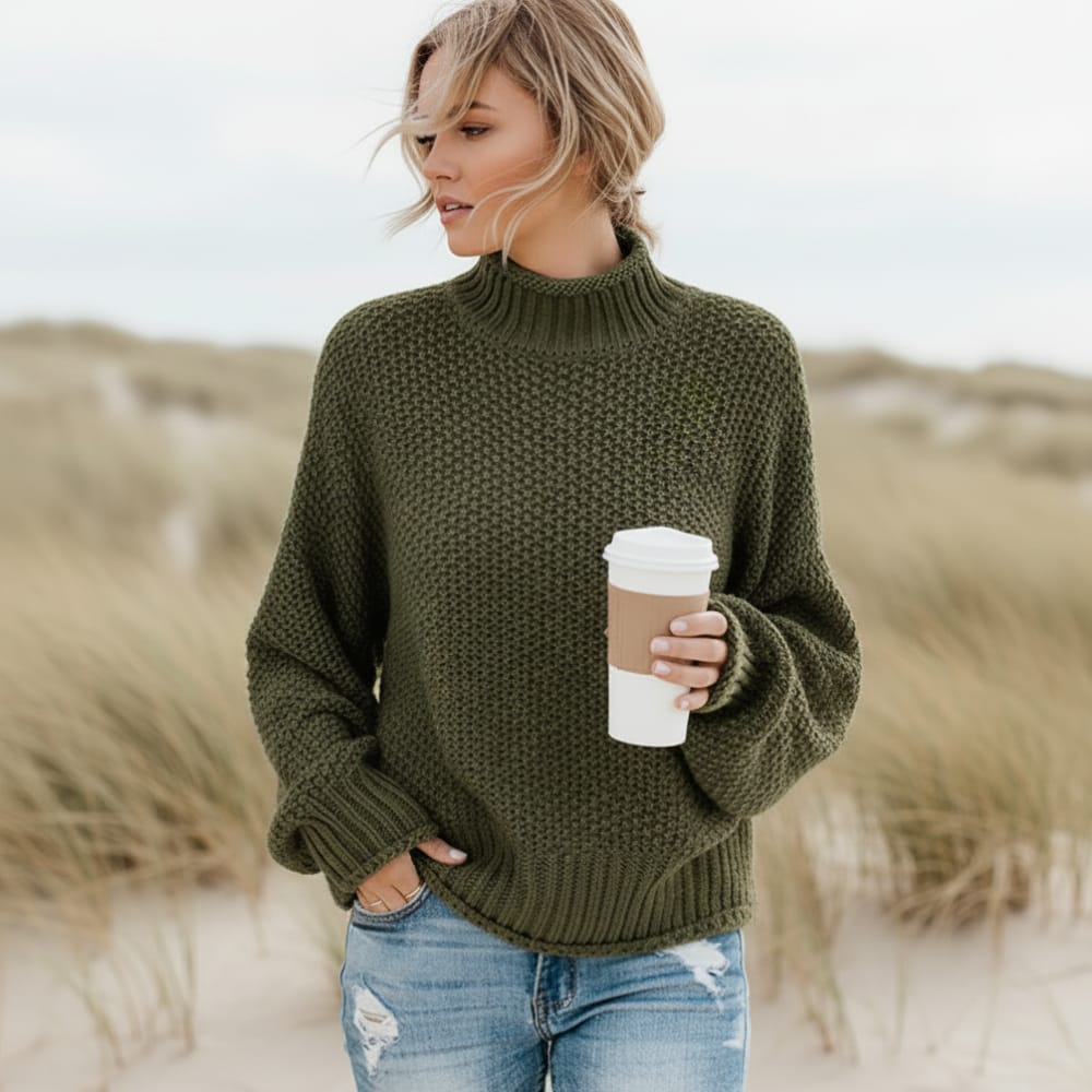 Olive green chunky knit turtleneck sweater with balloon sleeves and a relaxed, oversized fit worn outdoors.