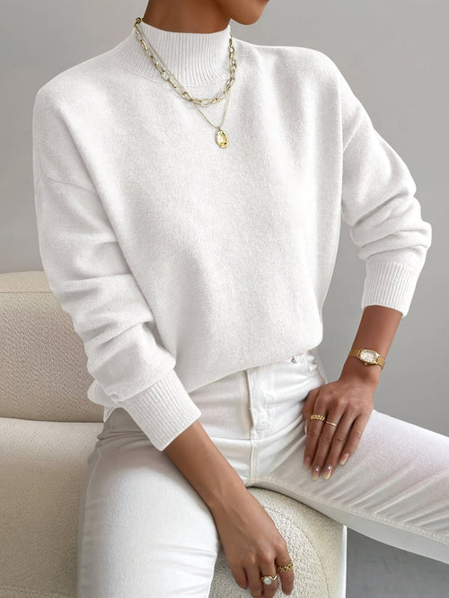 White knit turtleneck sweater with a relaxed dropped-shoulder fit, ribbed collar, and cuffs in a soft, textured fabric.