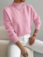 Soft pink knit turtleneck sweater with a relaxed dropped-shoulder fit, ribbed cuffs, and a high neckline.