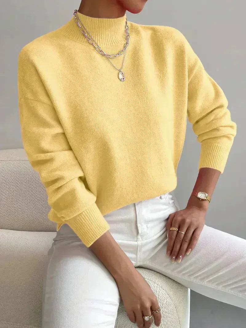 Soft yellow knit turtleneck sweater with a relaxed dropped-shoulder fit, ribbed collar, and cuffs worn with white jeans.