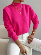Hot pink ribbed knit turtleneck sweater with a relaxed dropped-shoulder fit and defined cuffs, styled with white denim.
