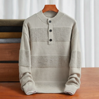Beige cotton knit henley sweater with textured stripe panels, a three-button placket, and ribbed trim on a wooden table.