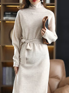 Beige high-neck wool midi sweater dress with a waist-defining tie, featuring a soft knit texture and tailored fit.