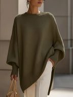 Olive green oversized knit sweater with a relaxed poncho silhouette, ribbed cuffs, and a high-low hemline.