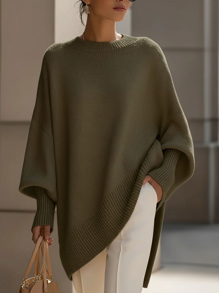 Olive green oversized knit sweater with a relaxed poncho silhouette, ribbed cuffs, and a high-low hemline.