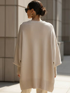 Oversized cream ribbed knit sweater with a loose poncho silhouette, wide sleeves, and structured hem detailing.
