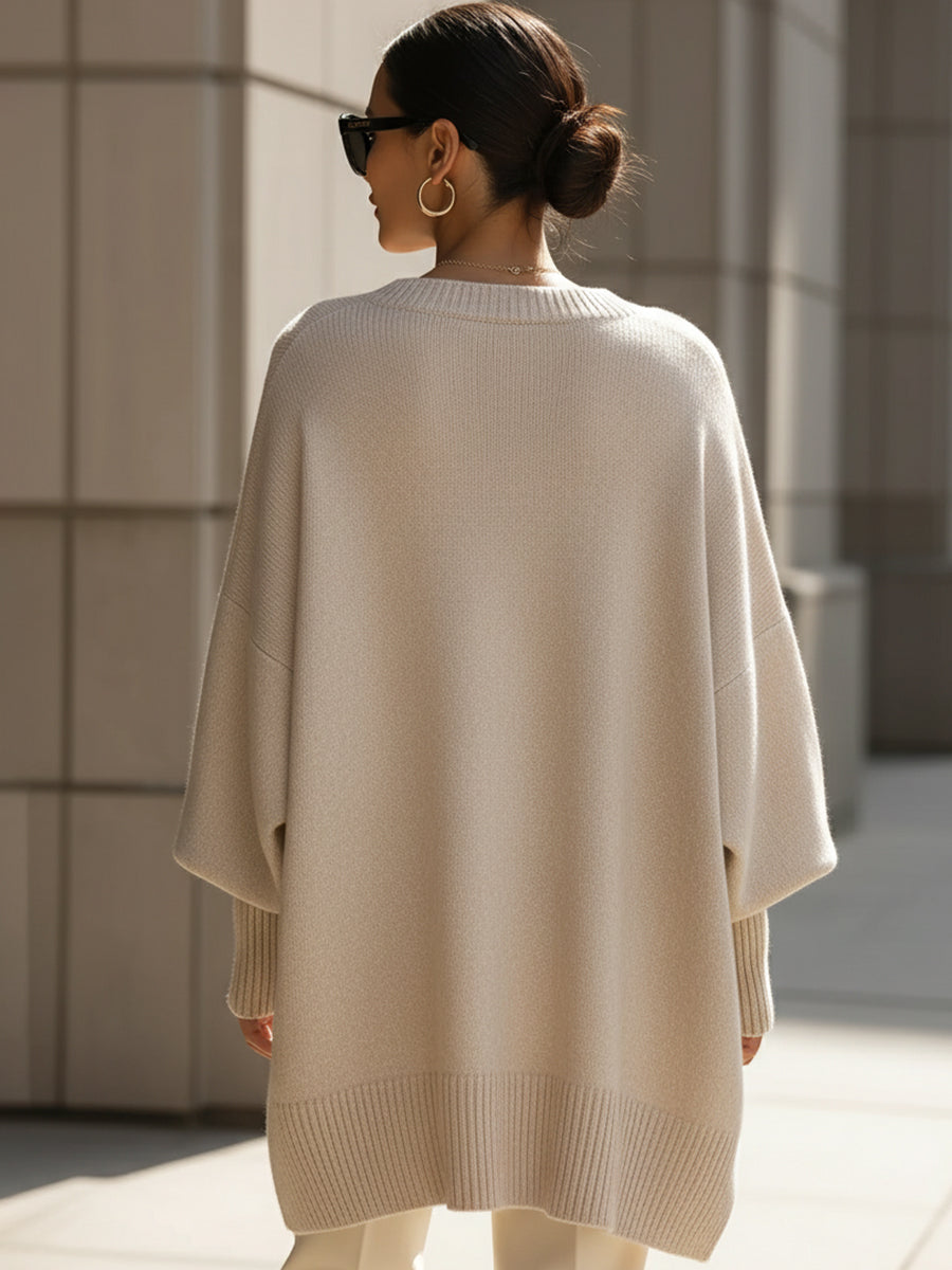 Oversized cream ribbed knit sweater with a loose poncho silhouette, wide sleeves, and structured hem detailing.