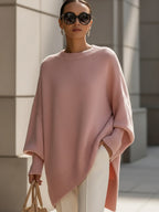 Oversized blush pink ribbed knit sweater with a relaxed poncho silhouette, drop shoulders, and structured cuffs.