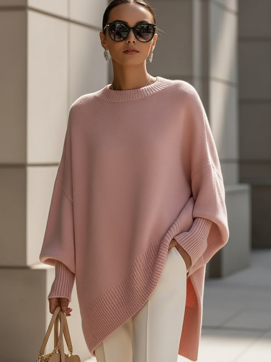 Oversized blush pink ribbed knit sweater with a relaxed poncho silhouette, drop shoulders, and structured cuffs.