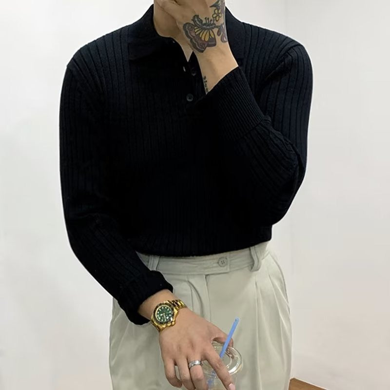 Black long-sleeve polo sweater in vertical rib-knit with a lapel collar and button placket, worn with light trousers.