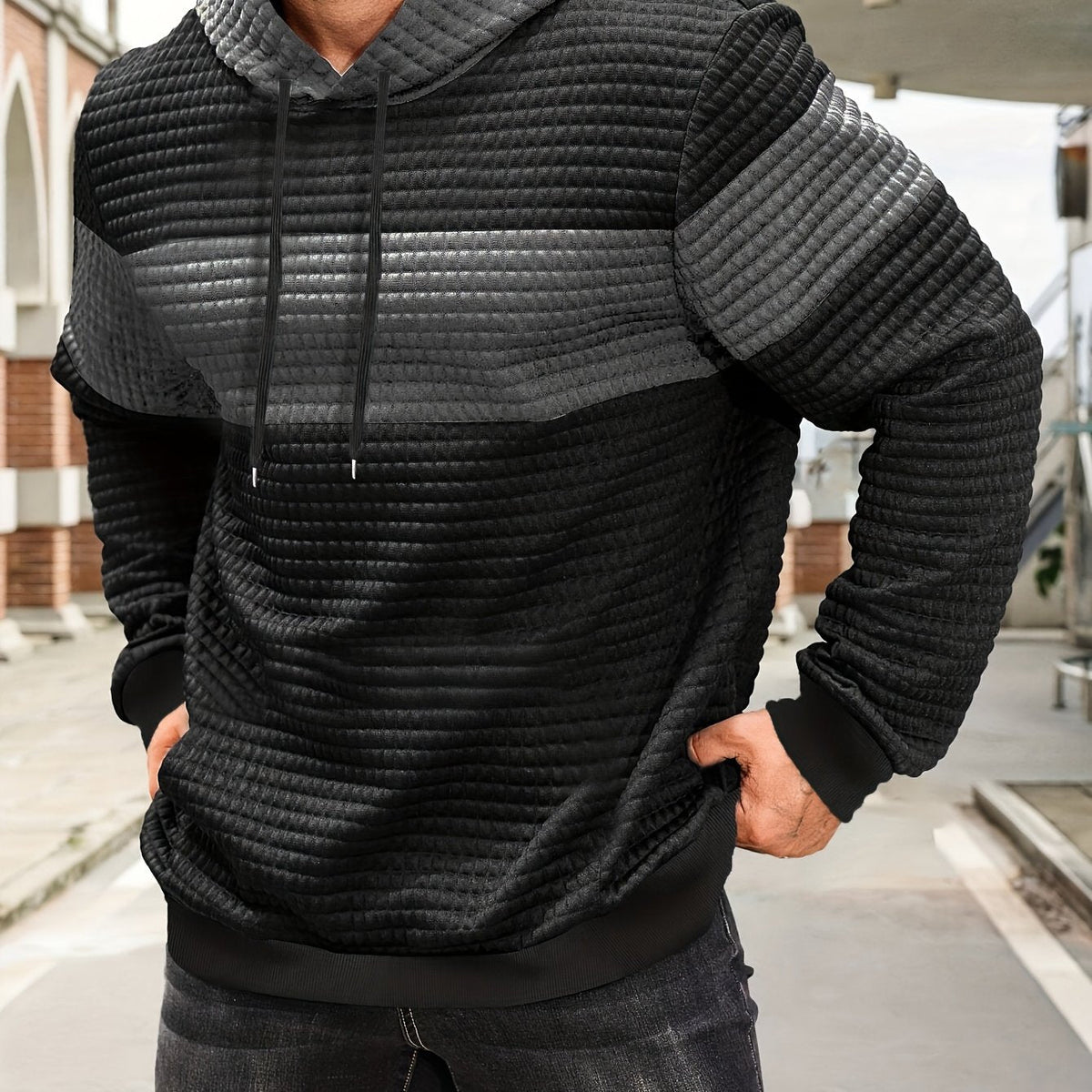 Colorblock Waffle-Knit Hoodie – Black hoodie worn by a male model with a dark gray contrast chest panel and front pocket