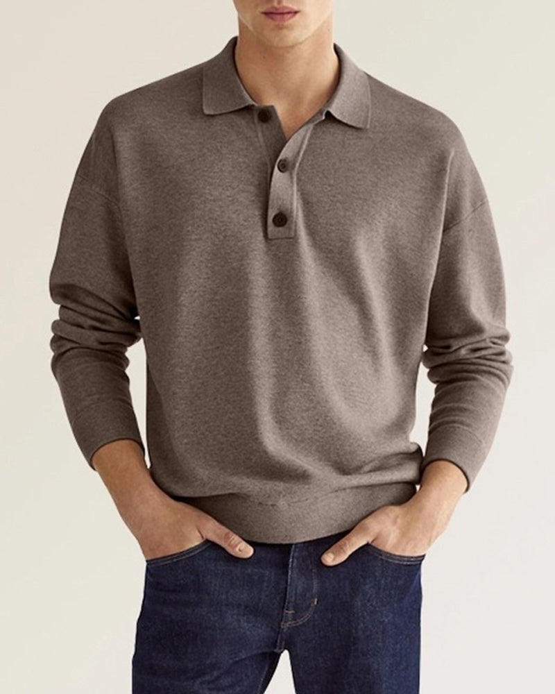 Taupe long-sleeve knit polo with a dropped-shoulder fit, ribbed collar, and two-button placket worn with dark denim.
